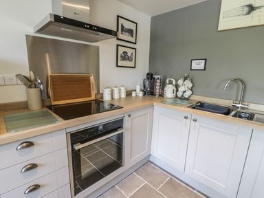 A kitchen with an oven stove coffee maker kettle sink and cups at Swn yr Afon in Beddgelert
