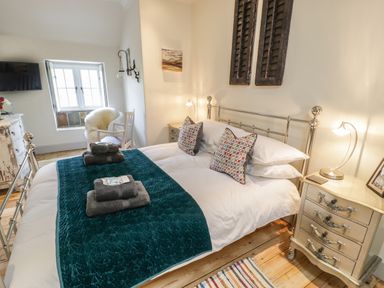 A bedroom with a double bed pillows lamps bedside tables and a window at Swn yr Afon in Beddgelert