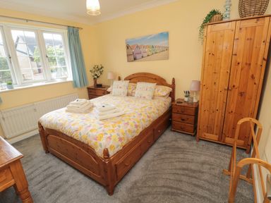 A bedroom with a double bed wooden furniture and a window at Island View Cottage in High Hauxley near Amble