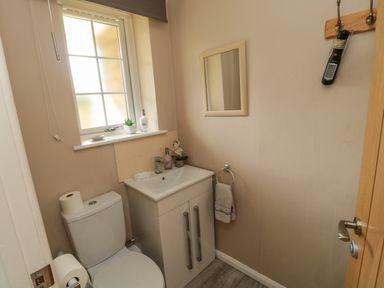 A small bathroom with a toilet a sink cabinet mirror window and a hand towel at Island View Cottage in High Hauxley near Amble