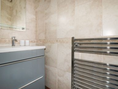 A bathroom with a sink cabinet and a chrome towel radiator at Garden View in Quintrell Downs near Newquay