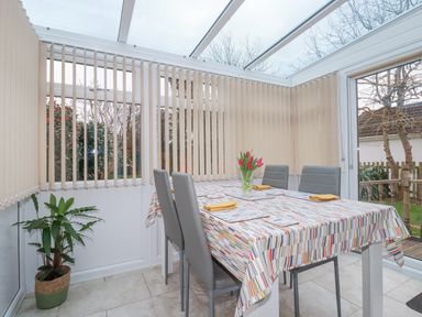 A dining area with a table covered by a colorful tablecloth four chairs and a vase with flowers at Garden View in Quintrell Downs near Newquay