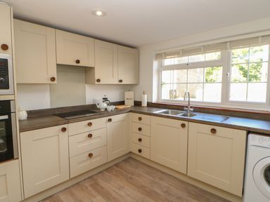 A kitchen with cream cabinets wood handles a double sink and a washing machine under the counter at The Forge in Allendale