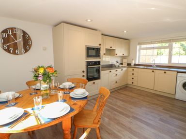 A kitchen with a dining table set with plates and glasses and a bouquet of flowers on the table at The Forge in Allendale