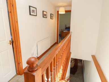 A hallway with wooden banister and three framed pictures on the wall at The Forge in Allendale