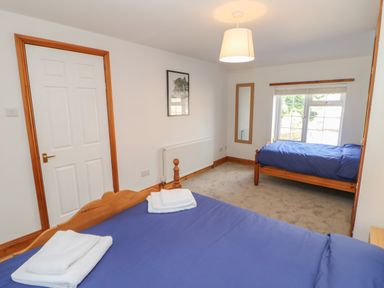 A bedroom with two wooden beds with blue bedding a door a wall mirror and a window at The Forge in Allendale