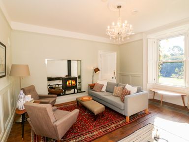 A living room with a fireplace two armchairs a sofa and a chandelier at Carley's Bridge House Carley's Bridge near Enniscorthy County Wexford