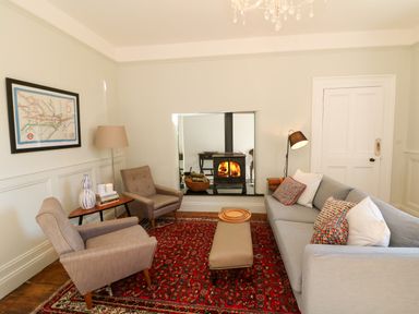 A living room with two armchairs a sofa a red patterned rug a wood burning stove and a framed map on the wall at Carley's Bridge House in Carley's Bridge near Enniscorthy County Wexford
