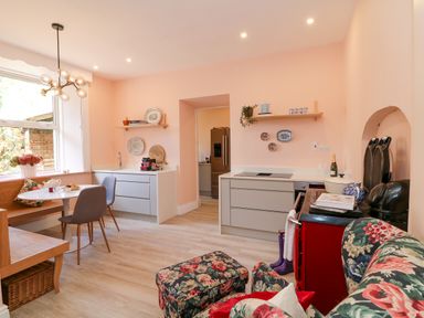 A kitchen with a dining table and chairs floral sofa and ottoman and shelves with kitchenware at Carley's Bridge House in Carley's Bridge near Enniscorthy County Wexford