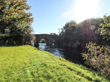 A stone bridge over a river with grass and trees on the riverbank at Carley's Bridge House in Carley's Bridge near Enniscorthy County Wexford