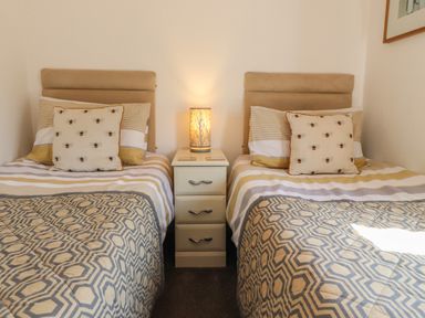 A bedroom with two single beds separated by a nightstand and a lamp at Doormouse Lodge in South Lakeland Leisure Village