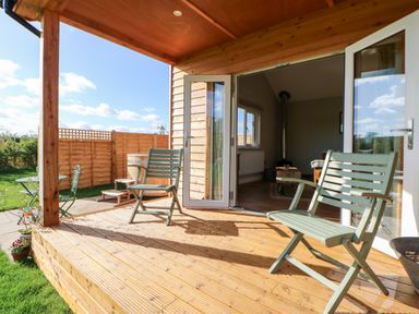 A wooden porch with two chairs and an open door leading to a living room at Rising Sun in Kirkbymoorside