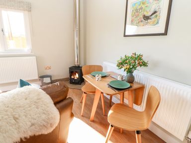 A dining area with a wooden table and two chairs next to a stove and a window at Rising Sun in Kirkbymoorside