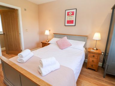 A bedroom with a double bed two wooden bedside tables with lamps and rolled towels on the bed at Rising Sun in Kirkbymoorside