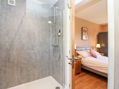 A bathroom with a glass shower and a view into a bedroom with a bed and bedside tables at Rising Sun in Kirkbymoorside
