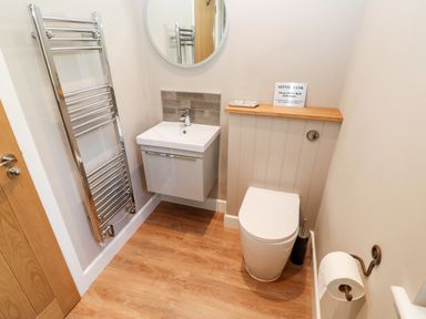 A bathroom with a toilet sink round mirror and towel rail at Rising Sun in Kirkbymoorside