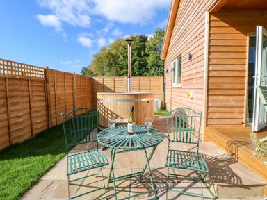 A patio with a metal table and two chairs a wooden hot tub and a wooden fence at Rising Sun in Kirkbymoorside