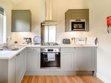 A kitchen with grey cabinets a stove an oven a microwave a kettle a toaster and a bread box at Peep o Day in Kirkbymoorside