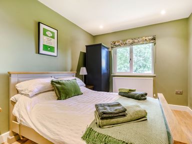 A bedroom with a bed with pillows and folded towels near a window with a radiator at Peep o Day in Kirkbymoorside