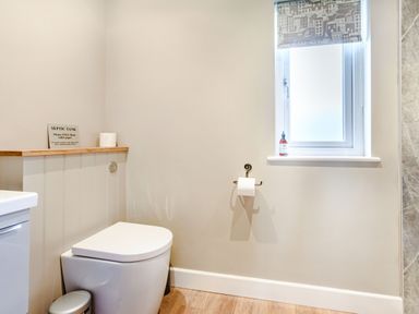A bathroom with a toilet paper holder and a window above the toilet at Peep o Day in Kirkbymoorside