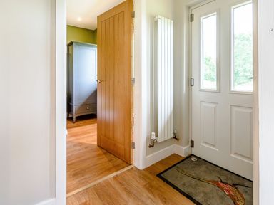 A hallway with a wooden door leading to a room with a wardrobe and a white door with windows at Peep o Day in Kirkbymoorside