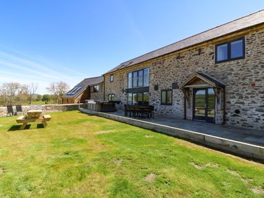 Stone exterior of a house with patio furniture and a picnic table on a lawn at Bwthyn Y Bugail Shepherds Cottage in Pedairffordd near Llanrhaeadr Ym Mochnant