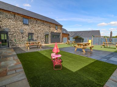 An outdoor space with picnic tables playground equipment and a small pink children's table and chairs at Bwthyn Y Bugail Shepherd's Cottage in Pedairffordd near Llanrhaeadr-Ym-Mochnant