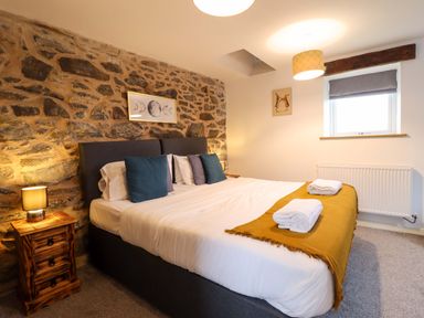 A bedroom with stone wall and bed at Bwthyn Y Bugail (Shepherd's Cottage) Pedairffordd near Llanrhaeadr-Ym-Mochnant