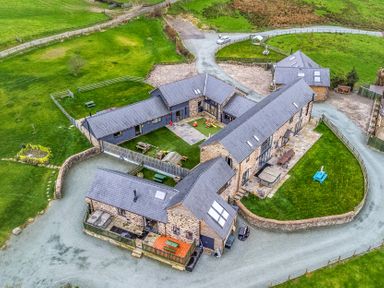 An outdoor view of a property with multiple buildings and landscaped garden at Bwthyn Y Bugail (Shepherd's Cottage) Pedairffordd near Llanrhaeadr-Ym-Mochnant