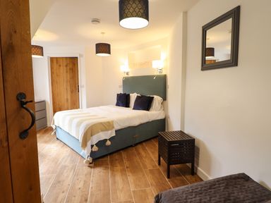A bedroom with a bed beside a wooden door and a mirror on the wall at Y Granar Llanrhaeadr-Ym-Mochnant