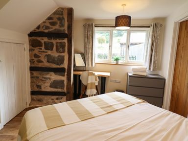 A bedroom with a bed a desk chair dresser and window at Y Granar The Granary in Llanrhaeadr-Ym-Mochnant