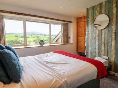 A bedroom with a double bed and large window overlooking fields at Y Granar in Llanrhaeadr-Ym-Mochnant