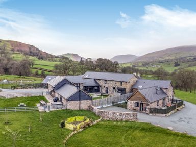 An outdoor view of a property with surrounding fields and mountains at Y Granar (The Granary) Llanrhaeadr-Ym-Mochnant