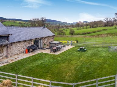 An outdoor space with a table and chairs at Y Granar (The Granary) Llanrhaeadr-Ym-Mochnant