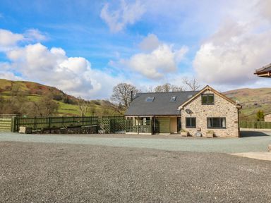 A stone house with a slate roof and gravel driveway in a rural setting at Y Stabl (The Stable) in Llanrhaeadr-Ym-Mochnant