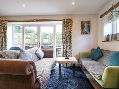 A living room with two sofas facing each other with cushions and a small wooden table between at Y Stabl (The Stable) in Llanrhaeadr-Ym-Mochnant