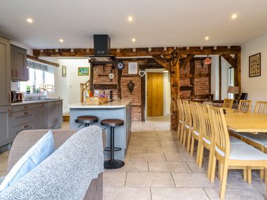 A kitchen and dining area with wooden beams and a dining table with chairs at Y Stabl The Stable in Llanrhaeadr Ym Mochnant