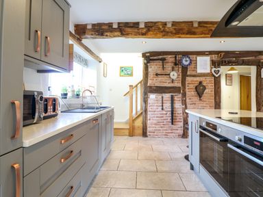 A kitchen with grey cabinets copper handles a microwave toaster dish rack and an oven by Y Stabl The Stable in Llanrhaeadr-Ym-Mochnant