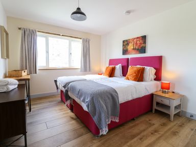 A bedroom with two single beds with pink headboards and orange pillows at Y Stabl The Stable in Llanrhaeadr-Ym-Mochnant
