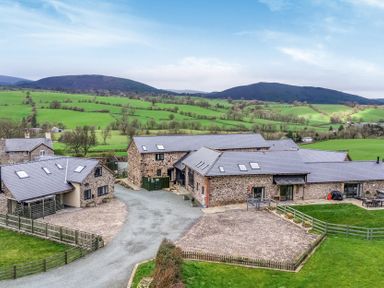 An outdoor area with barns and greenery at Y Stabl (The Stable) Llanrhaeadr-Ym-Mochnant