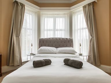 A bedroom with a bed two rolled towels bedside tables and lamps at Sunnymeade in Buxton Norfolk