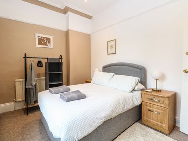 A bedroom with a double bed bedside tables clothes rack and framed pictures at Sunnymeade in Buxton Norfolk