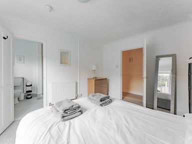 A bedroom with a bed with towels on it a chest of drawers a floor mirror and an en suite bathroom at Sunnymeade in Buxton Norfolk