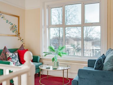 A sitting area with two armchairs a round glass coffee table with a potted plant and a window at Sunnymeade in Buxton Norfolk
