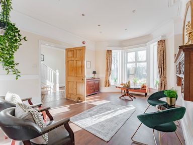 A sitting room with two black chairs and two green chairs around a table near windows at Sunnymeade in Buxton Norfolk