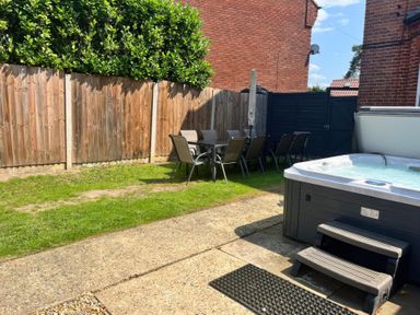 A garden with a hot tub and a dining area at Sunnymeade in Buxton, Norfolk
