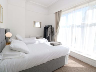 A bedroom with two beds, a lamp, and a clothes rack at Sunnymeade in Buxton, Norfolk