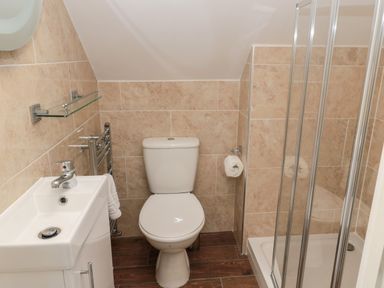 A bathroom with a white toilet sink and glass shower enclosure at Jubilee House in Embleton