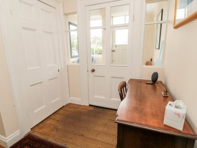 A small wooden desk with a chair tissue box and speaker near a white door with windows at Jubilee House in Embleton