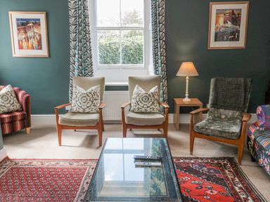 A living room with chairs a glass coffee table and framed artwork at Jubilee House in Embleton